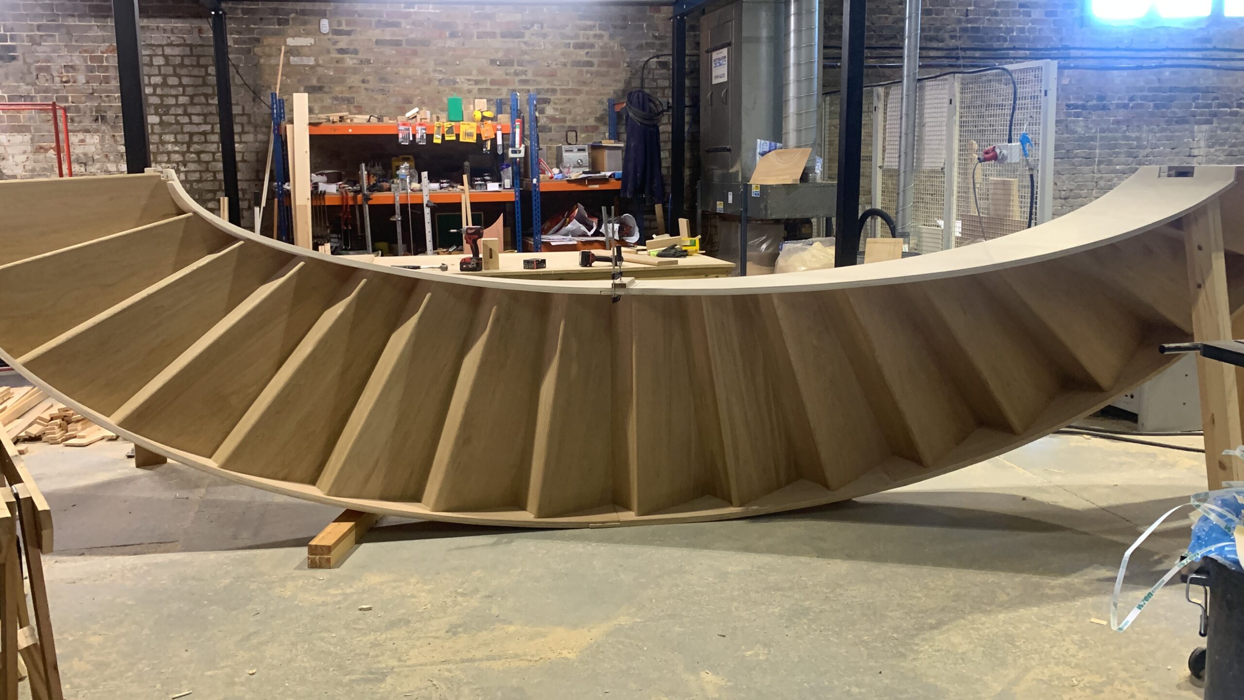 Full curved oak staircase flight with treads and risers, assembled on trestles in the DAB Stairs workshop