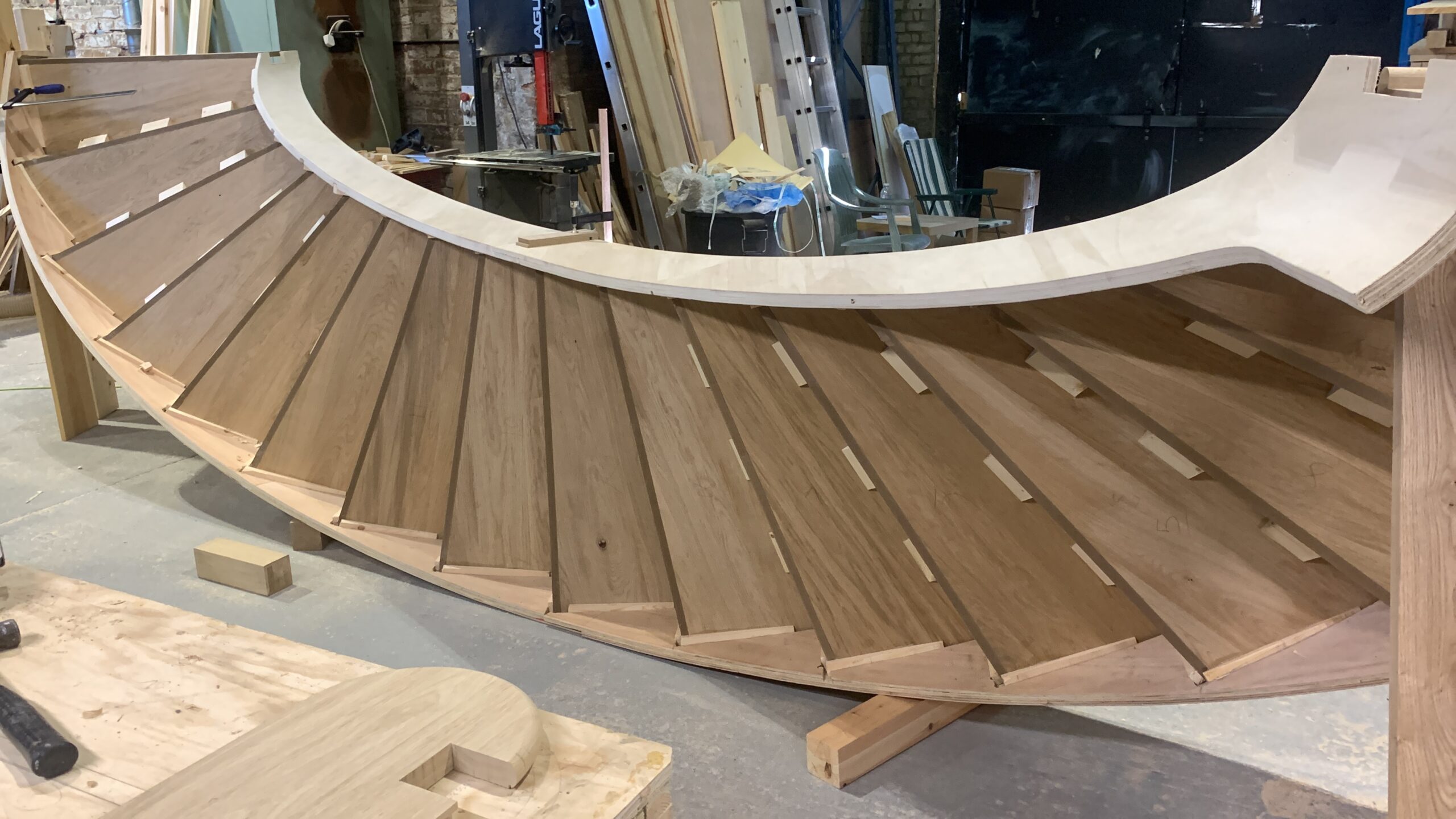 Solid oak treads following the curve of a bespoke staircase during dry assembly in the workshop