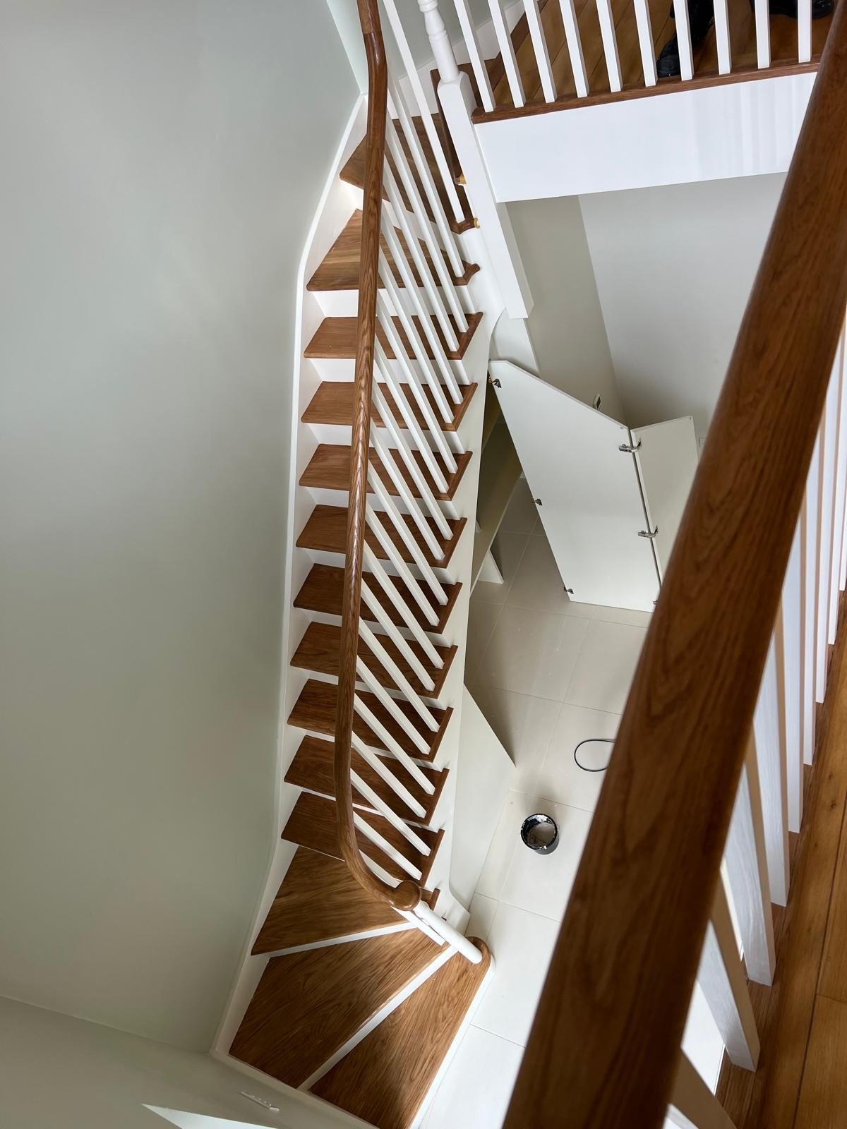 Curved wooden staircase with white railings