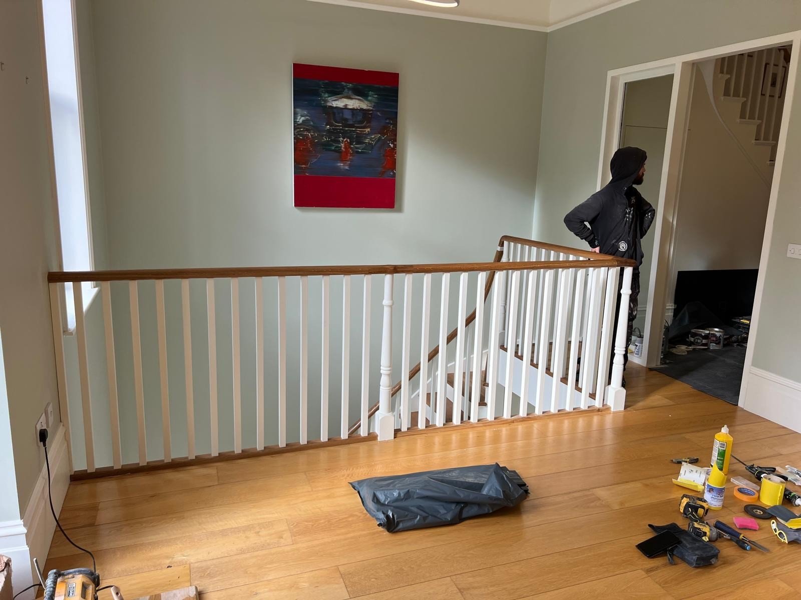 Renovation tools on wooden floor near staircase landing.