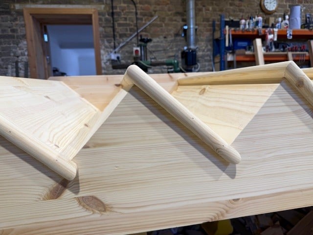 Wooden structure with angled beams in workshop.