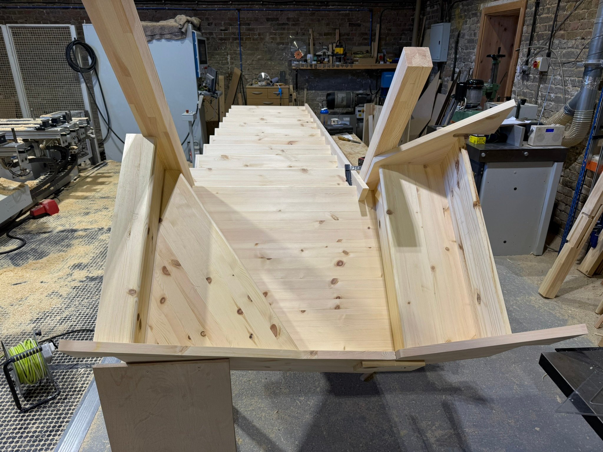 Unfinished wooden boat in workshop setting.