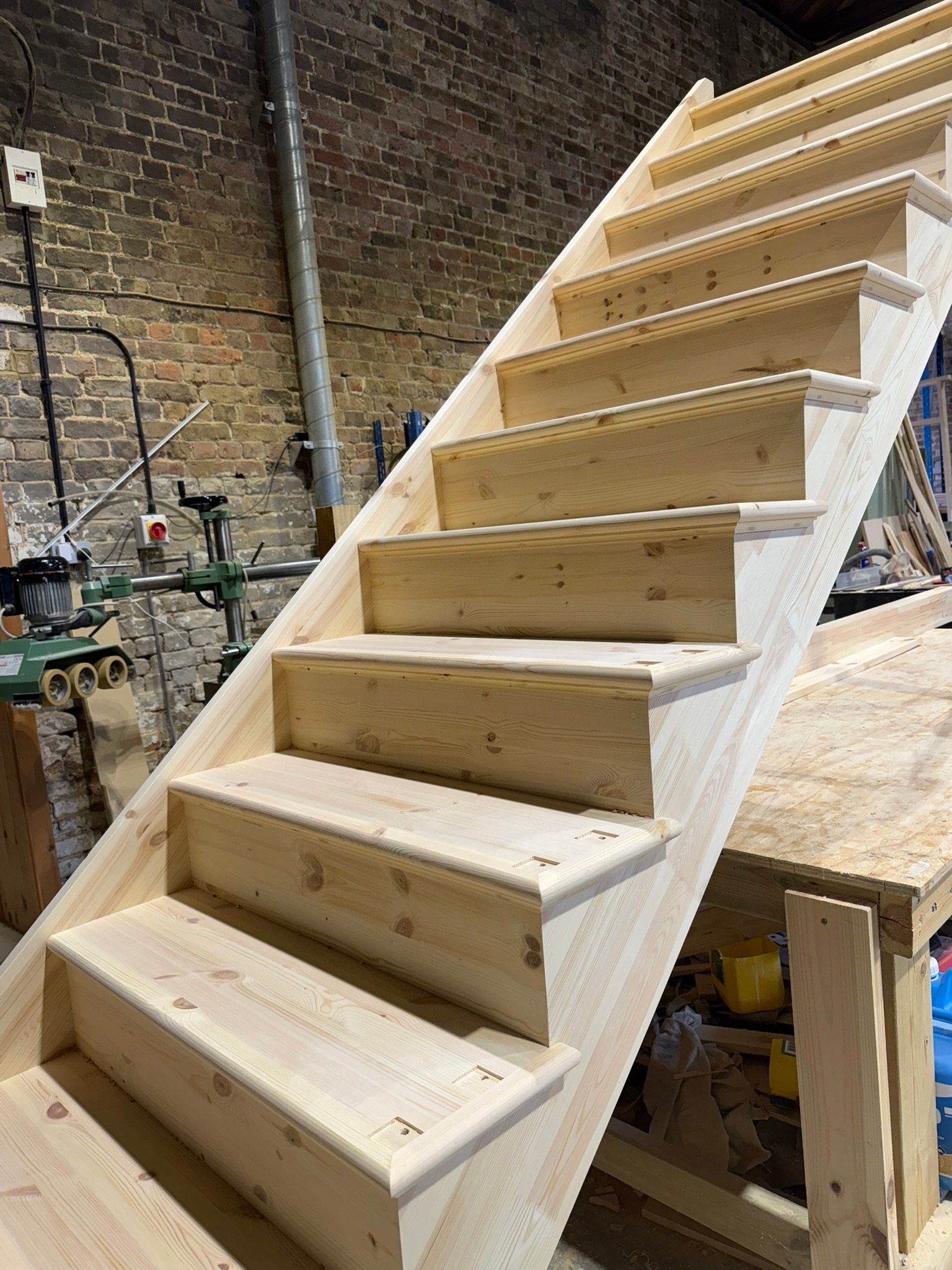Wooden staircase under construction in workshop.