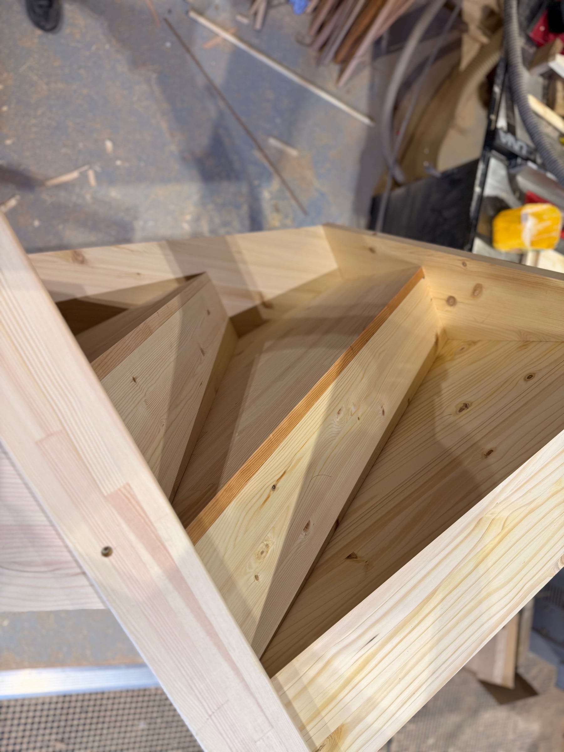 Back of a softwood cut string flight, showing the treads and risers framed between the strings